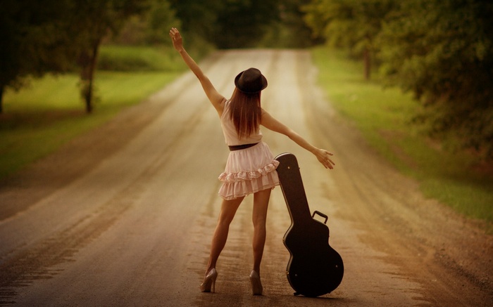 Woman with guitar case on a dirt road