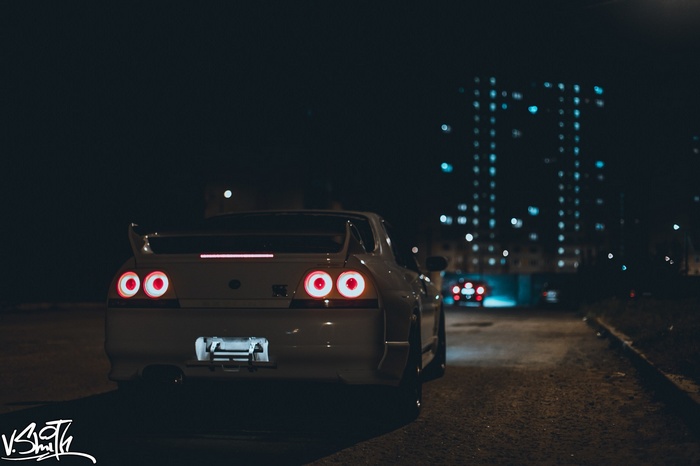 Nissan Skyline GT-R parked at night with city lights