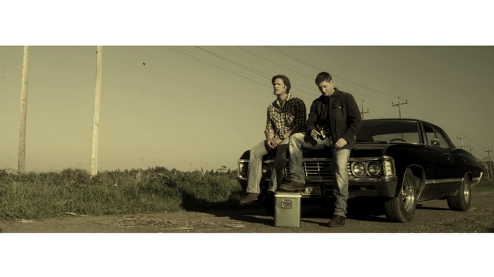 Dean and Sam Winchester sitting on a Chevrolet Impala