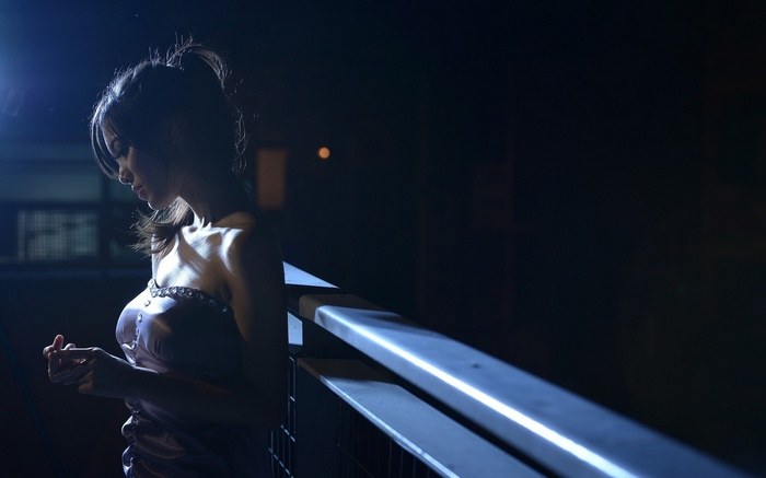 Woman in a dress standing by a railing at night