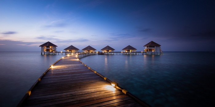 Overwater bungalows and walkway at dusk in the Maldives