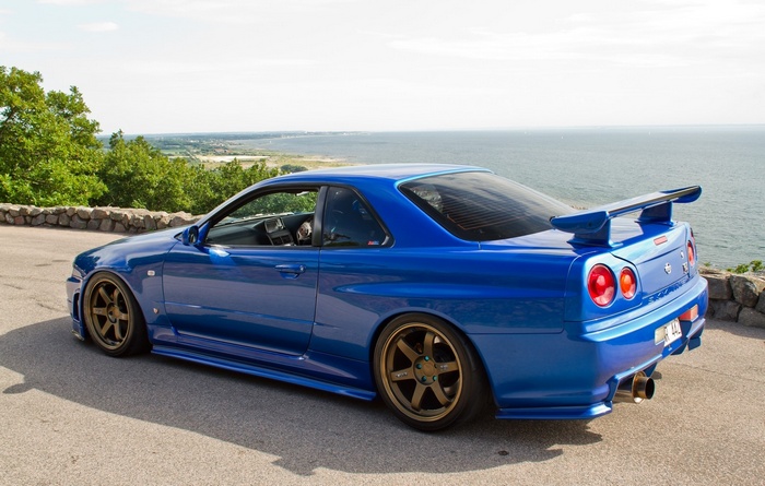 Blue Nissan Skyline GT-R R34 Nismo parked by the sea