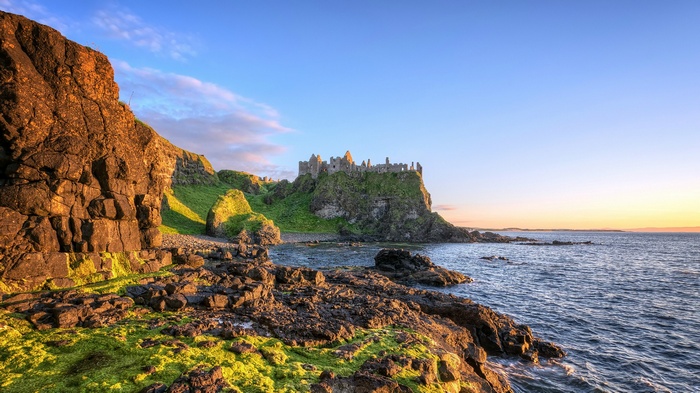 Dunluce Castle ruins on a rocky coast at sunset