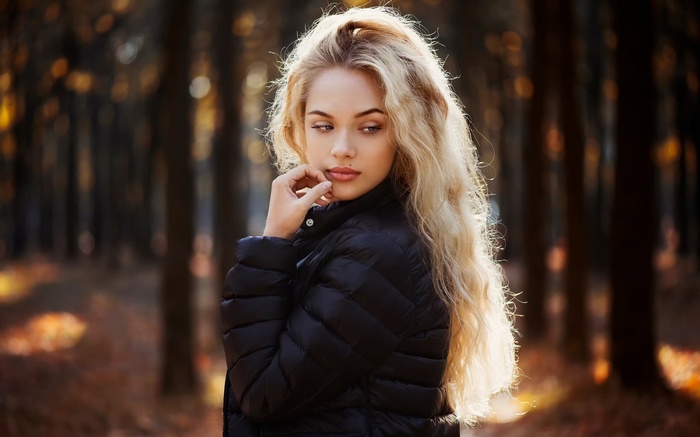Woman with long blonde hair in a black jacket outdoors