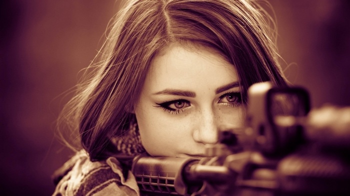 Woman aiming a rifle through a scope