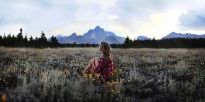 Woman sitting in a field with mountains