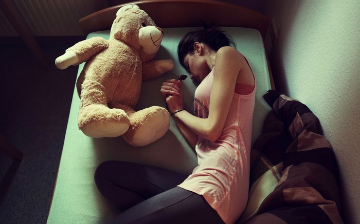 Woman sleeping with a teddy bear in bed