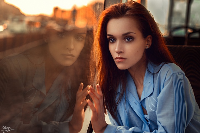 Redhead woman with blue eyes looking away by a window