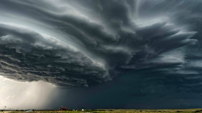 A dramatic supercell storm with heavy rain over a landscape.