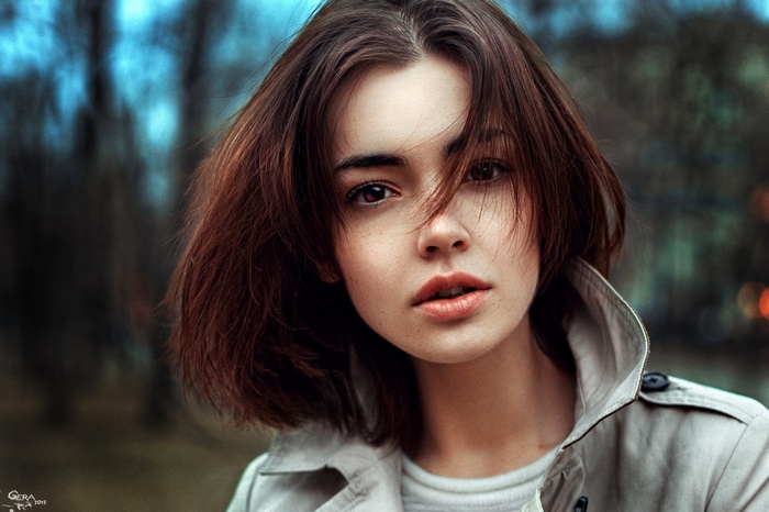 Woman with short brown hair and brown eyes wearing a trench coat