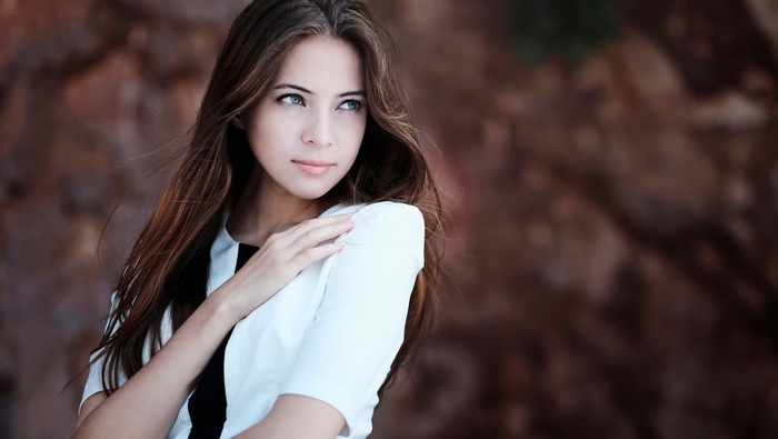 Woman with long brown hair and blue eyes outdoors
