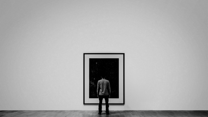 Man looking at a framed artwork in a minimalist gallery