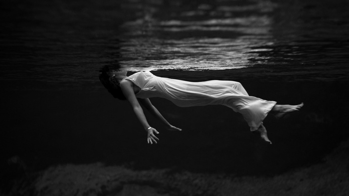 Woman in white dress floating underwater