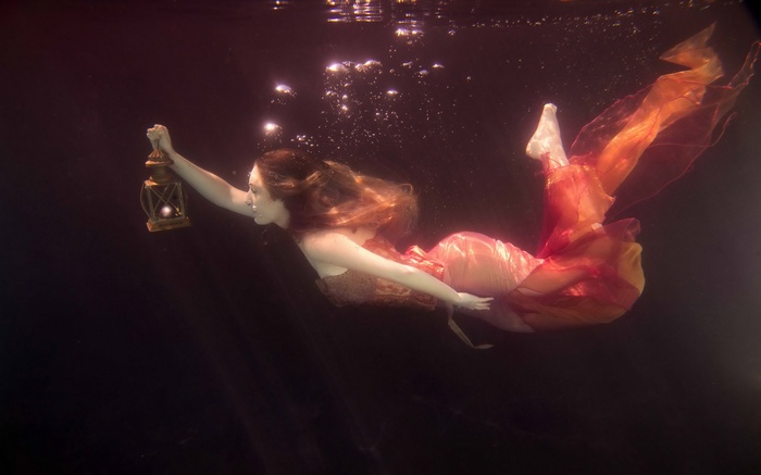Woman underwater holding a lantern