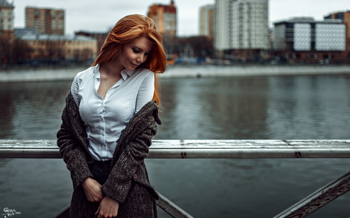 Redhead woman in a white shirt and coat on a bridge