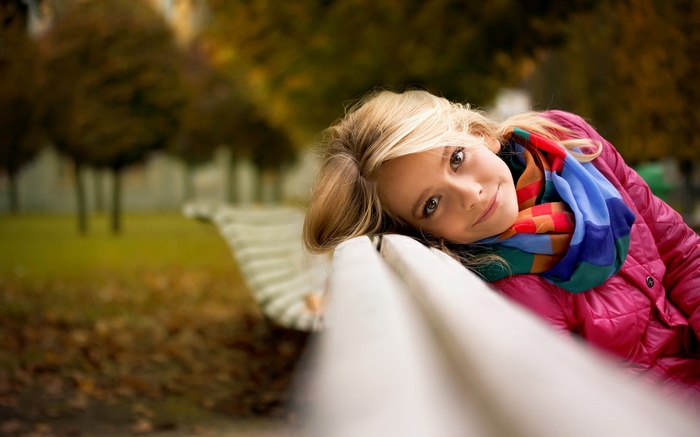 Woman in pink jacket and scarf on a park bench