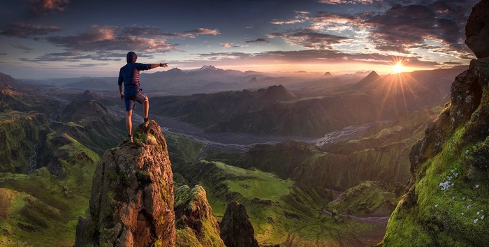 Man on a mountain peak overlooking a valley in Iceland