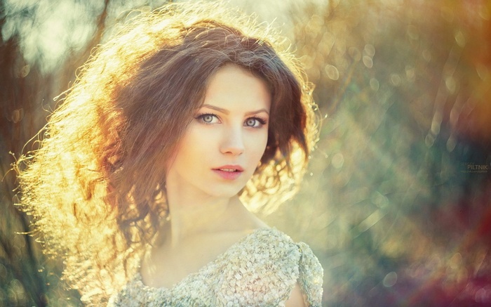 Woman with curly hair and blue eyes in sunlight