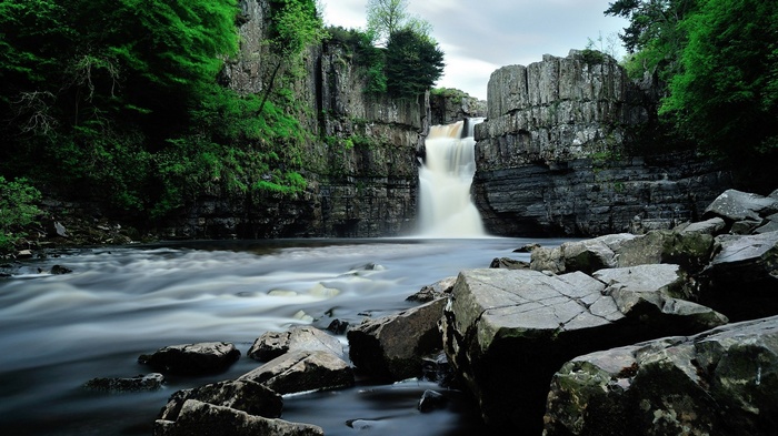 Waterfall cascading over rocky cliffs into a river