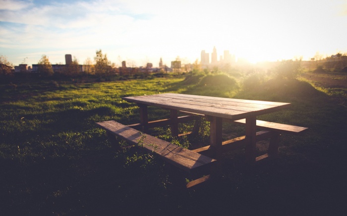 Picnic table in a grassy field at sunset