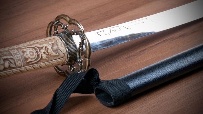 Katana sword with ornate handle on a wooden surface