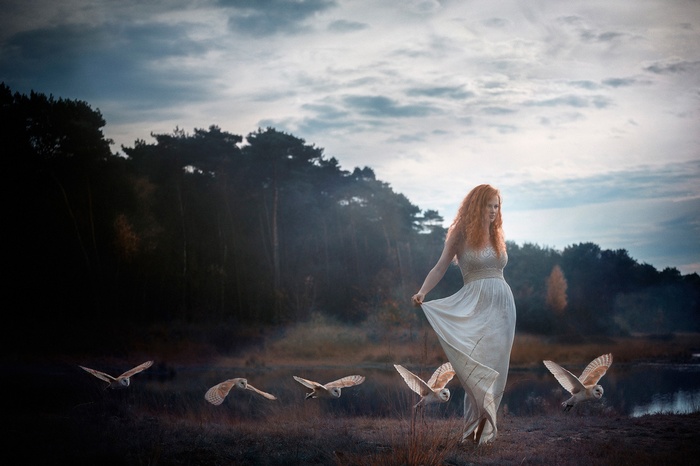 Woman in white dress with owls in forest