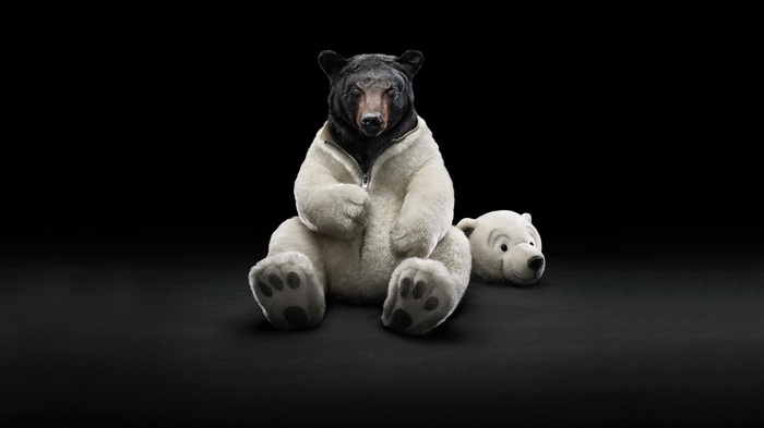 A black bear wearing a white jacket and a polar bear head