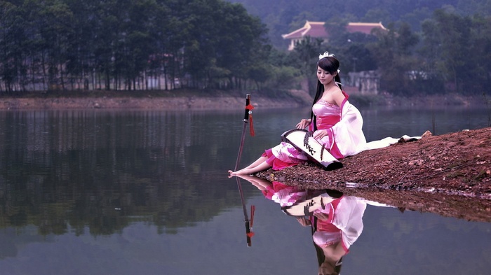 Woman in traditional Japanese attire by a lake with a katana