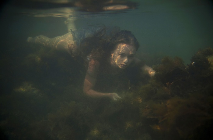 Woman swimming underwater near seaweed