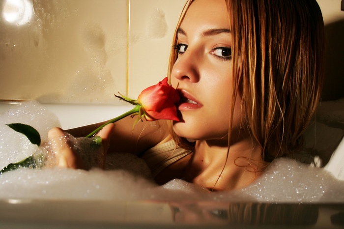 Woman in bubble bath holding a rose