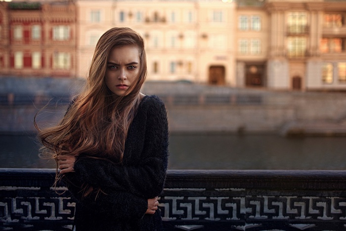 Woman with long hair in a black sweater by the river