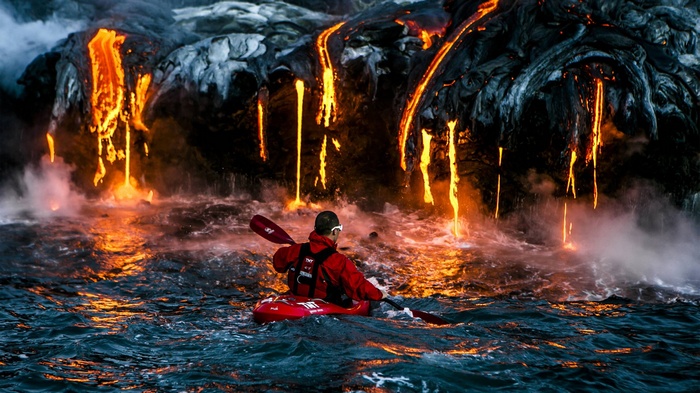 Man kayaking near lava flow from volcano