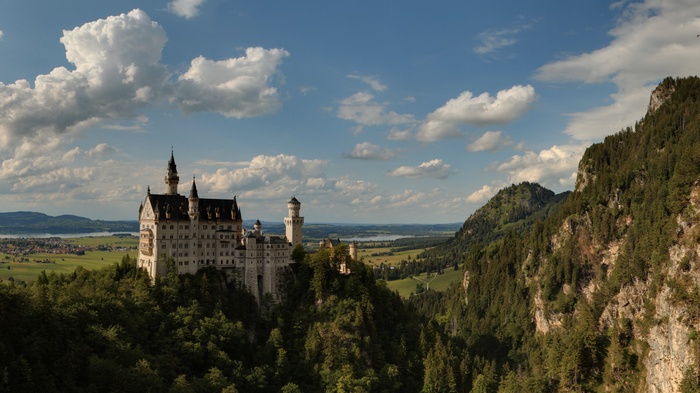 Neuschwanstein Castle on a green mountain under clouds