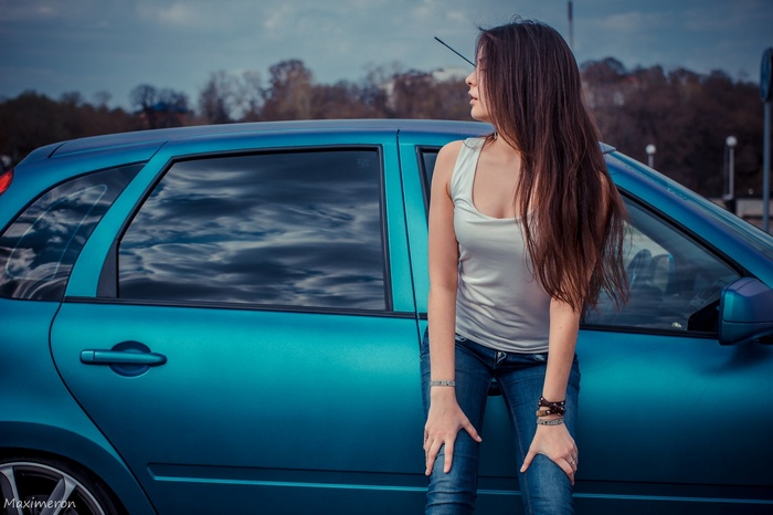 Woman leaning on a blue car