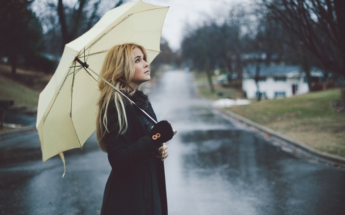 Woman with blonde hair holding a yellow umbrella in the rain