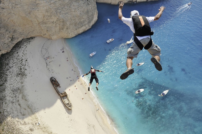 Two skydivers jump over a beach in Greece