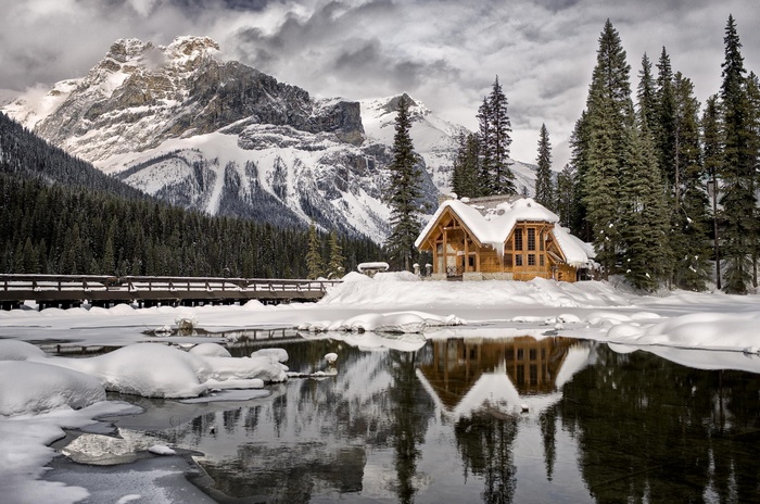 Snowy cabin on a frozen lake with mountains in British Columbia