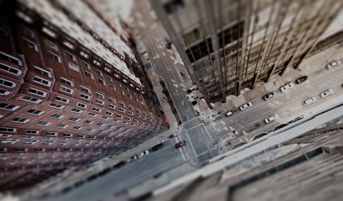 Tilt-shift aerial view of a city street with buildings and cars