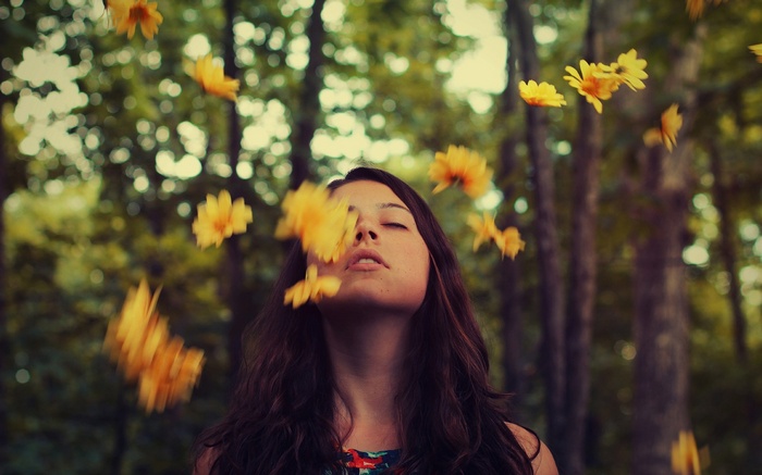 Woman with yellow flowers falling around her