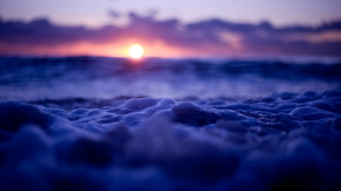 Sunset over the ocean with foamy waves