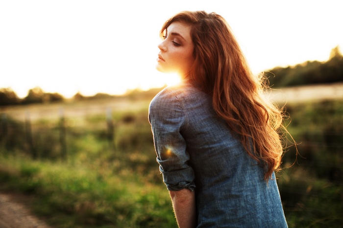 Woman with freckles and long red hair in sunlight