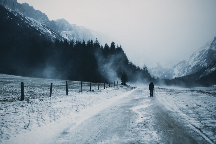 Person walking on a snowy road in the mountains