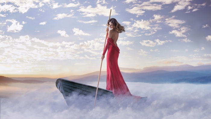 Woman in red dress on a boat in the clouds
