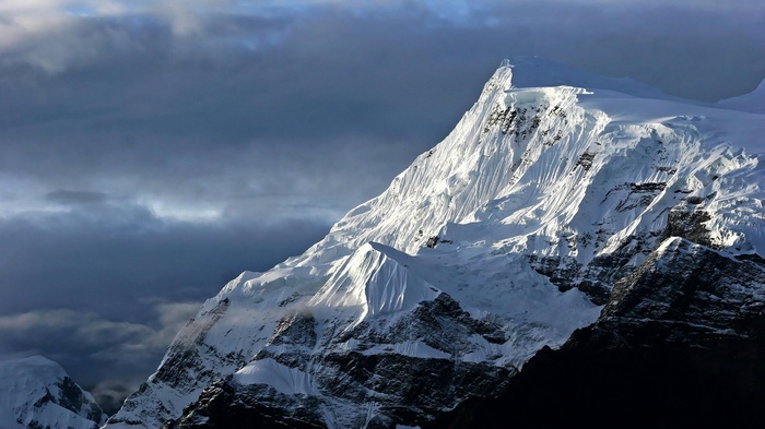 Snow-covered mountain peak under dramatic clouds