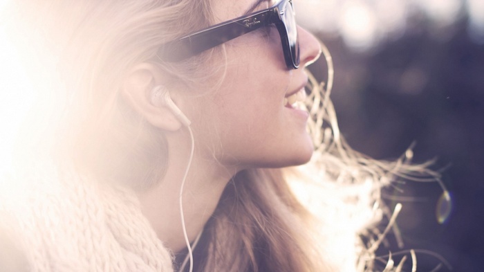 Woman wearing sunglasses and headphones listening to music
