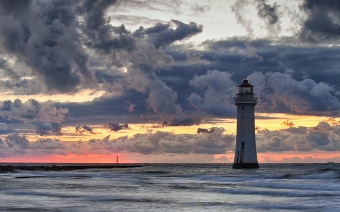 White lighthouse in the sea at sunset