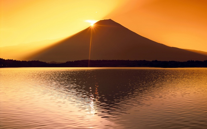 Mount Fuji silhouette at sunrise over a lake