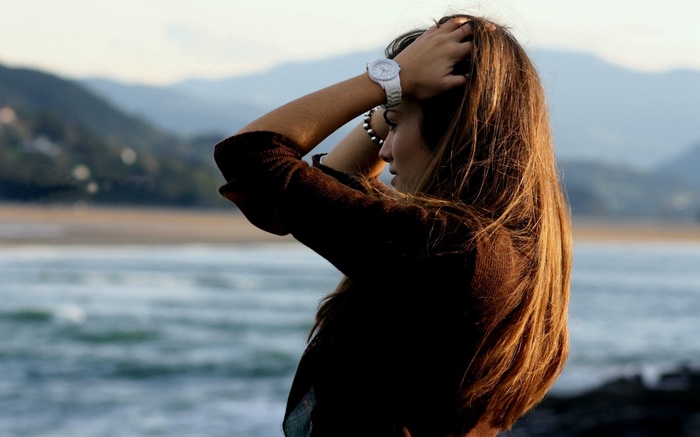 Woman with hands on head by the sea