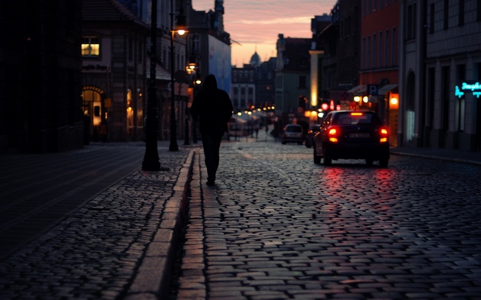 Person walking on a cobblestone street at dusk