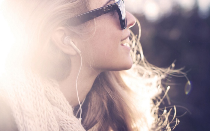 Woman wearing Rayban sunglasses and headphones